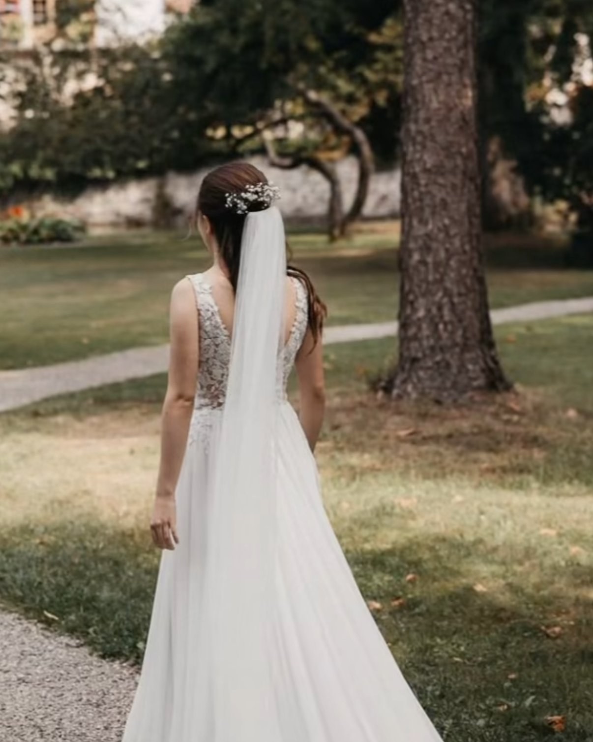 Braut im angepassten Kleid, Rückansicht im Garten