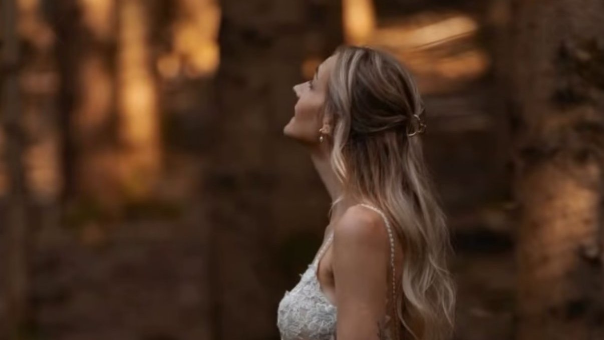 Braut im angepassten Brautkleid im abendlichen Wald